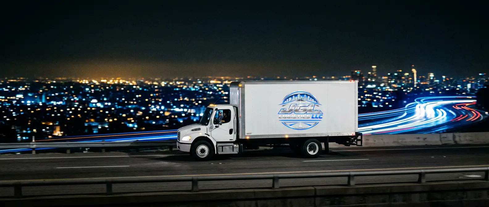 JGL Logistics box truck driving along a highway at night